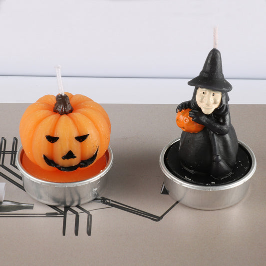 Halloween-themed candles, one shaped like a pumpkin and the other like a witch, on a neutral background.