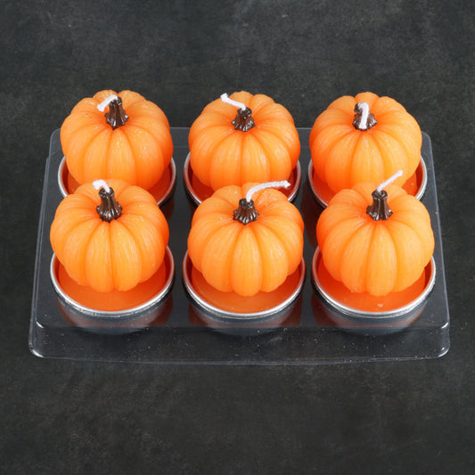 Six pumpkin-shaped candles in a clear plastic packaging on a dark background