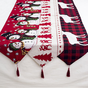 Christmas-themed table runner with snowmen, reindeer, and plaid patterns on a white surface.